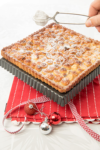 Dusting the Macadamia & Caramel Tart with icing sugar