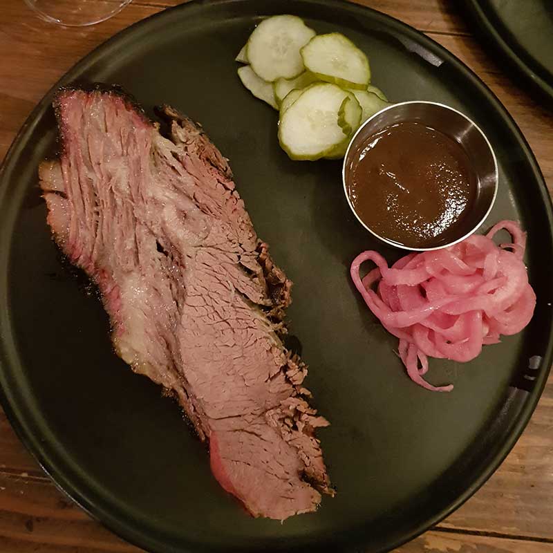 Meatmaiden Bar & Grill - 20-hour Smoked Rangers Valley Black Market Brisket with housemade pickles and Smokey BBQ Sauce.